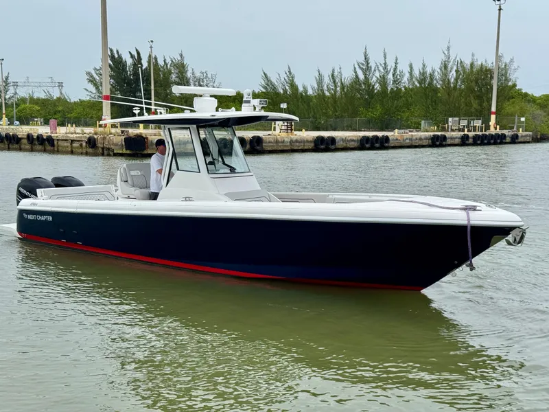 Slide: The Image of 2018 Intrepid 327 Center Console boat on calm water near a dock. - 2