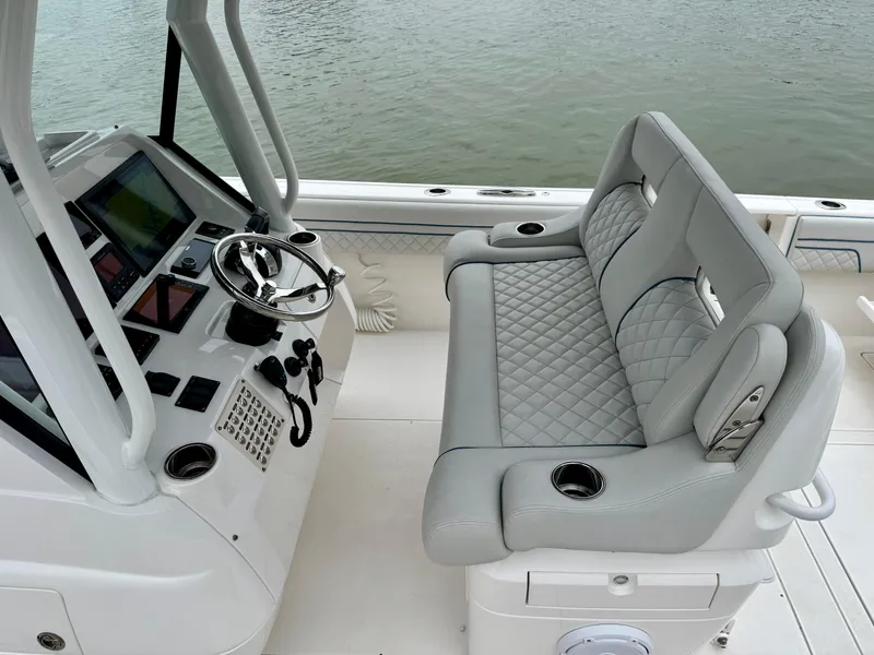 Slide: The Image of 2018 Intrepid 327 Center Console boat interior with steering wheel and cushioned seating. - 4