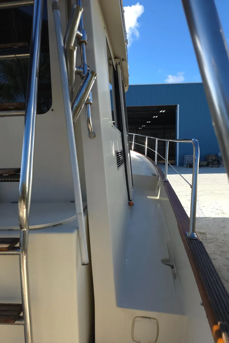 Slide: The Image of 2004 Legacy Sedan Flybridge yacht, side view with railing, near a blue warehouse. - 11