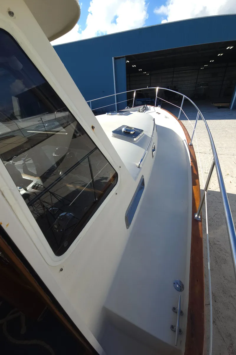 Slide: The Image of 2004 Legacy Sedan Flybridge boat docked near a blue warehouse under a clear sky. - 12
