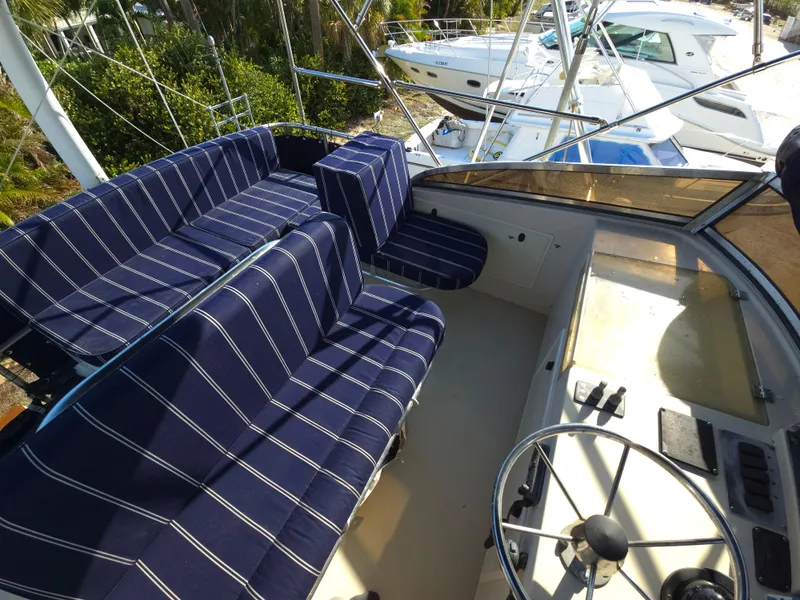 Slide: The Image of 2004 Legacy Sedan Flybridge with striped seating and steering wheel, docked near other boats. - 21
