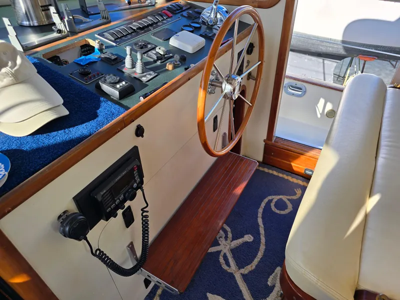 Slide: The Image of 2004 Legacy Sedan Flybridge helm with wooden wheel, control panel, and nautical-themed decor. - 29