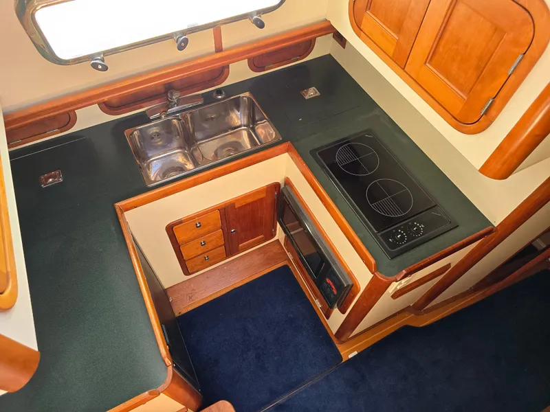 Slide: The Image of 2004 Legacy Sedan Flybridge kitchen with dual sinks, stovetop, and wooden cabinetry. - 33