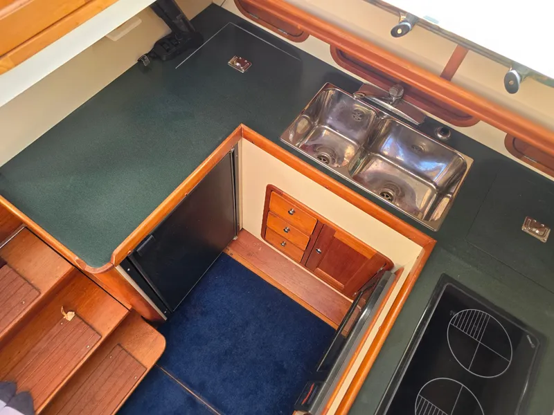 Slide: The Image of 2004 Legacy Sedan Flybridge kitchen with dual sinks, stove, and compact fridge. - 34