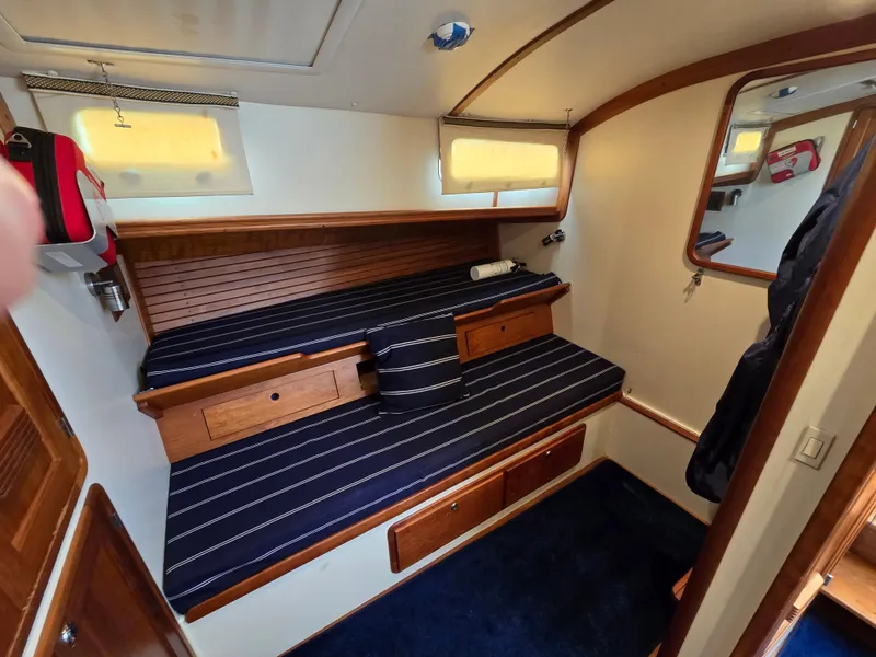 Slide: The Image of 2004 Legacy Sedan Flybridge cabin with striped bedding, wooden accents, and nautical decor. - 37