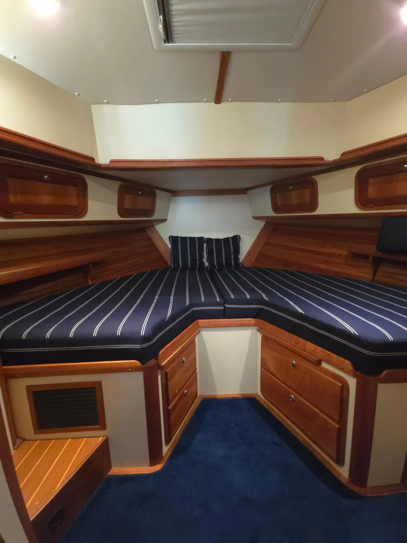 Slide: The Image of Interior cabin of 2004 Legacy Sedan Flybridge with striped bedding and wooden storage. - 42