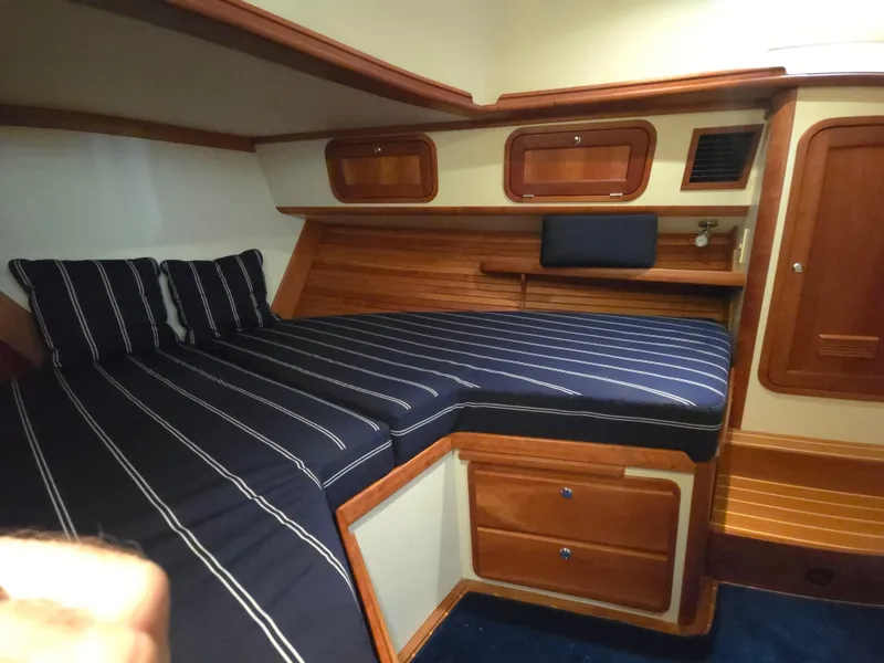 Slide: The Image of 2004 Legacy Sedan Flybridge cabin with striped bedding and wooden interior. - 44