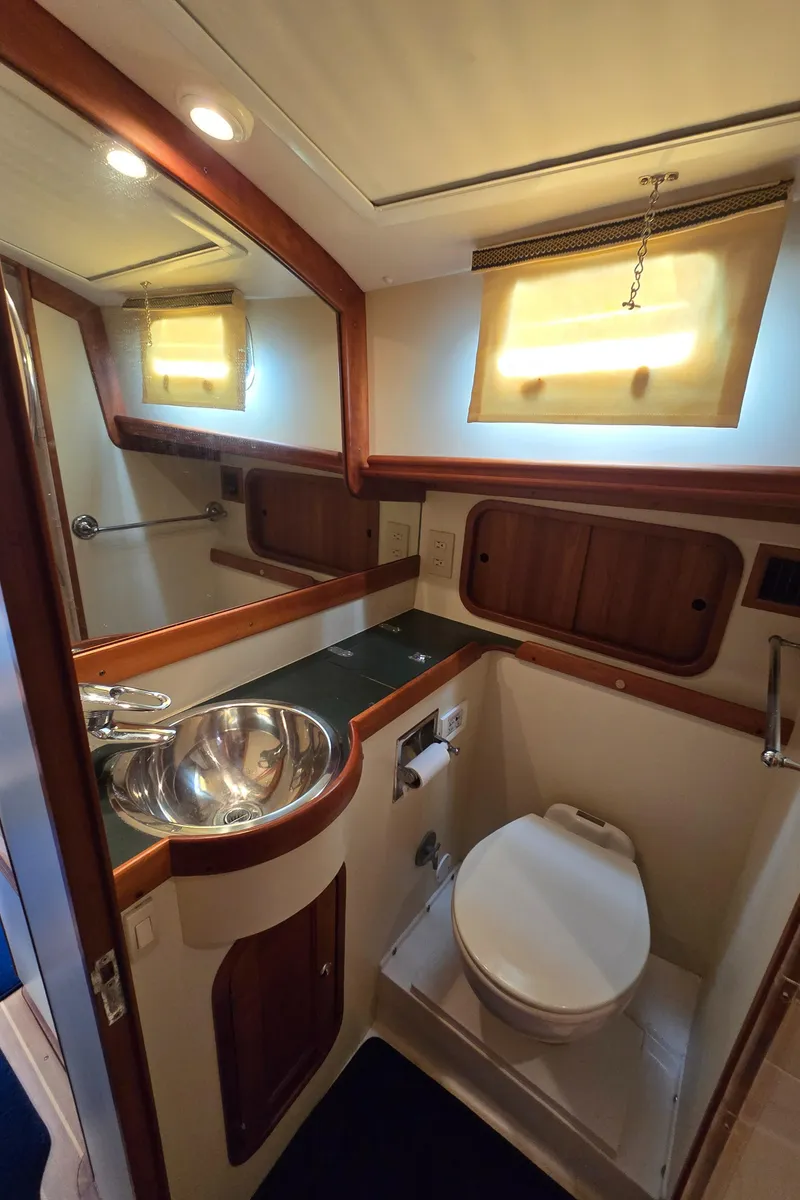 Slide: The Image of 2004 Legacy Sedan Flybridge bathroom with sink, toilet, and wooden accents. - 46