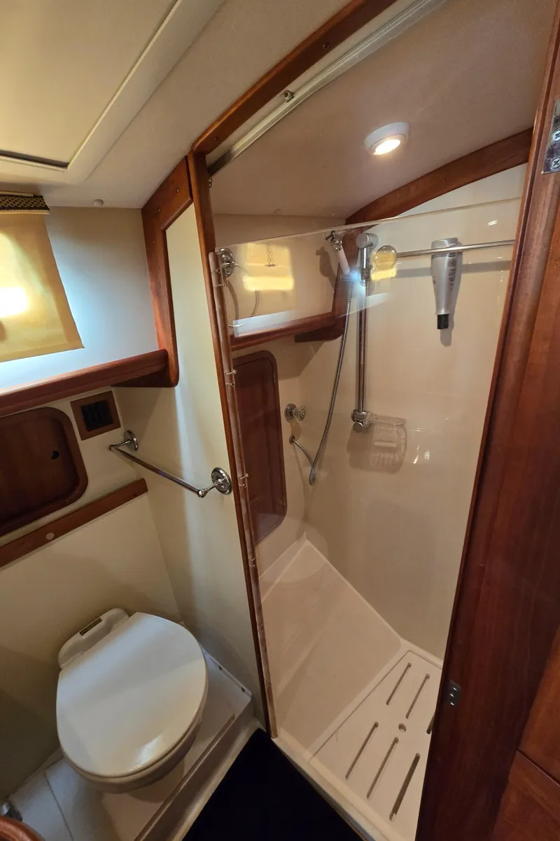 Slide: The Image of 2004 Legacy Sedan Flybridge bathroom with shower, wooden accents, and compact design. - 48