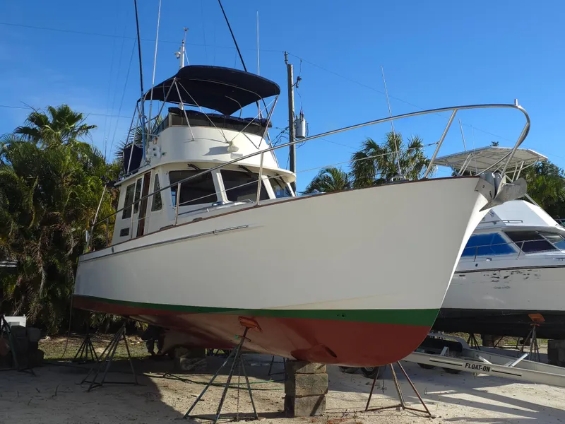 Slide: The Image of 2004 Legacy Sedan Flybridge boat on stands, surrounded by palm trees and clear blue sky. - 5