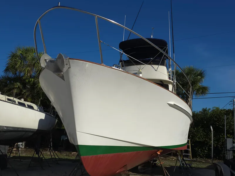 Slide: The Image of 2004 Legacy Sedan Flybridge boat on land, blue sky background, palm trees nearby. - 7