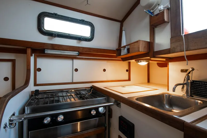 Slide: The Image of Compact kitchen in 1988 Morris Linda 28 sailboat with stove, sink, and wooden cabinetry. - 18