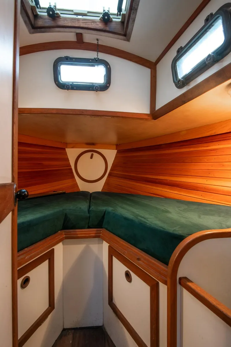 Slide: The Image of 1988 Morris Linda 28 sailboat cabin with wood paneling and green cushions. - 26