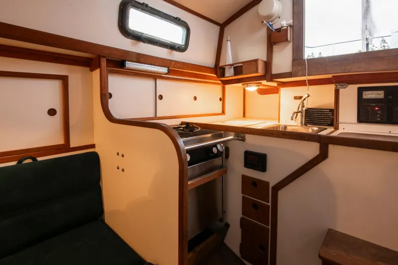 Slide: The Image of Compact kitchen area in a 1988 Morris Linda 28 sailboat with wood accents and stove. - 31