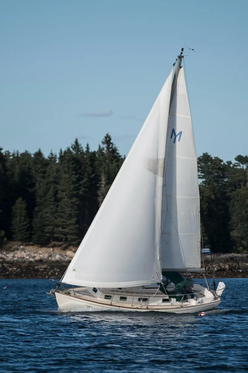 Slide: The Image of Sailboat Morris Linda 28, 1988 model, sailing on a calm lake with forested shoreline. - 32