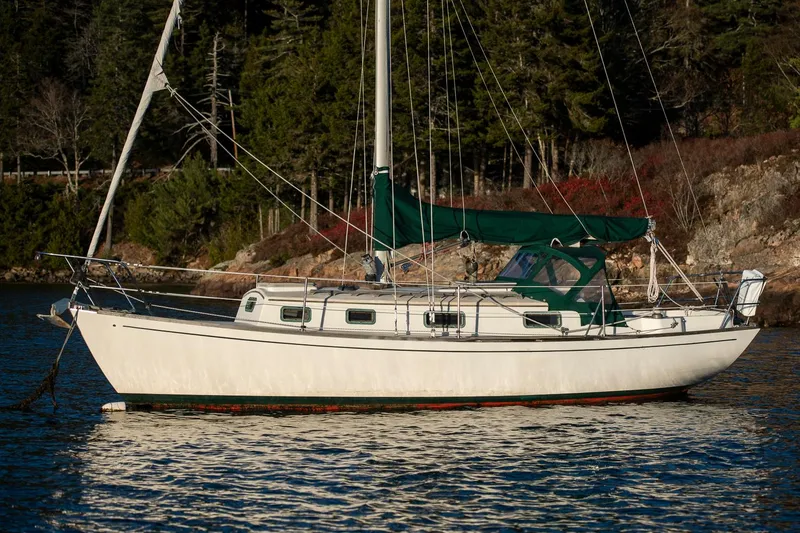 Slide: The Image of 1988 Morris Linda 28 sailboat on a calm lake, surrounded by forested shoreline. - 33