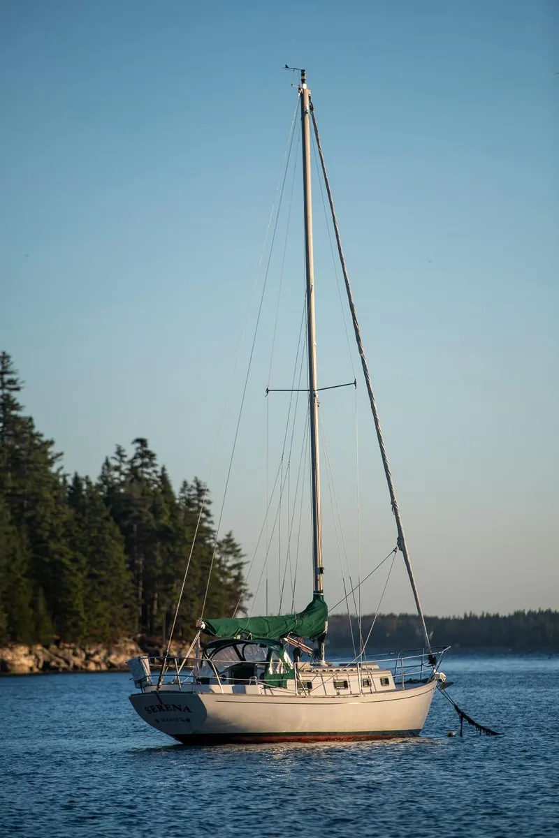 Slide: The Image of 1988 Morris Linda 28 sailboat anchored on calm water with forested shoreline. - 34