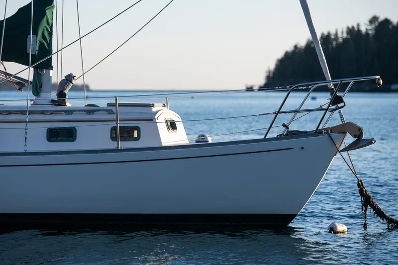 Slide: The Image of 1988 Morris Linda 28 sailboat anchored on calm water with forested shoreline in background. - 35