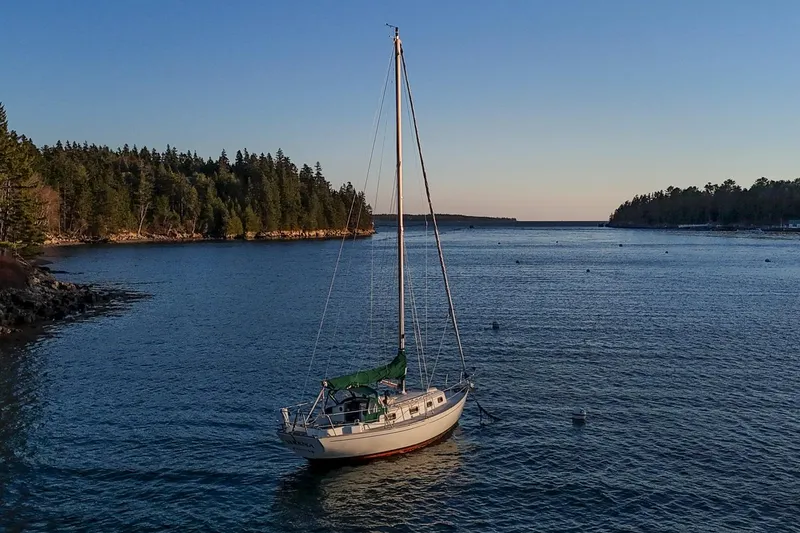 Slide: The Image of Sailboat Morris Linda 28, 1988 model, anchored in serene coastal waters at sunset. - 37