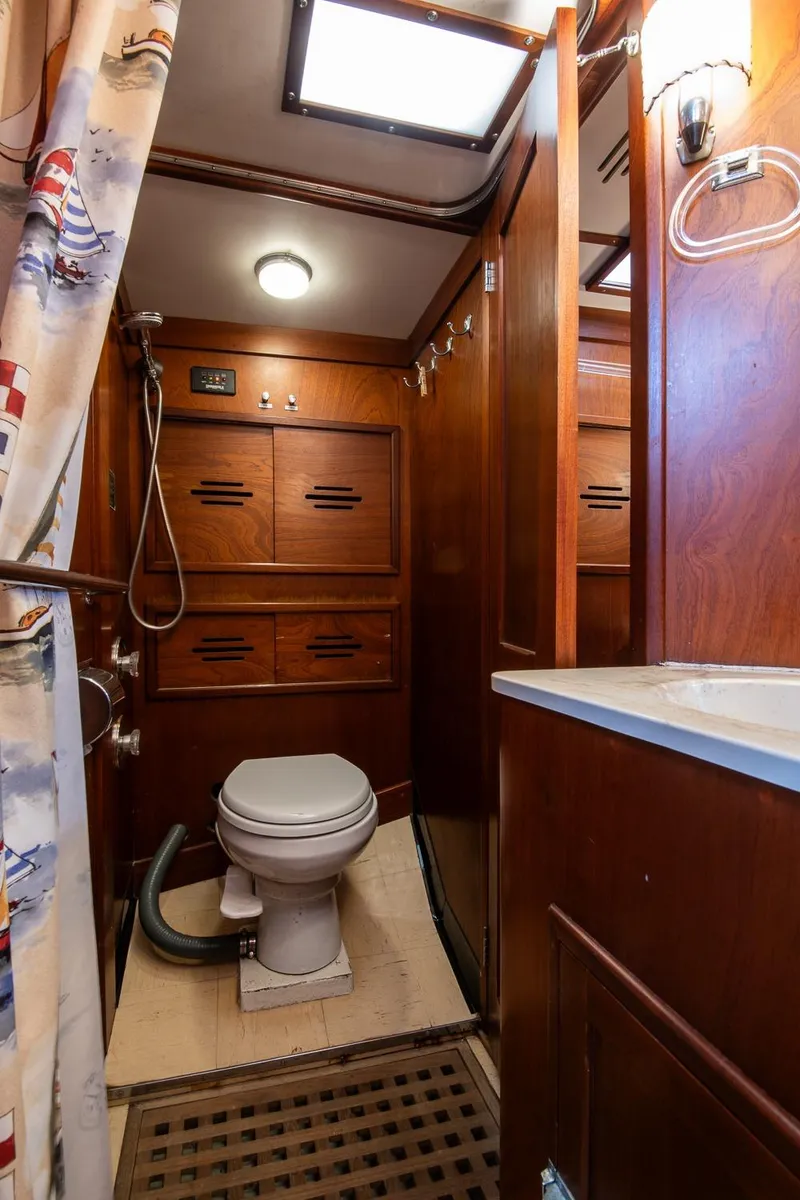 Slide: The Image of 1976 Hinckley SW50 yacht bathroom with wooden cabinetry and nautical-themed shower curtain. - 28