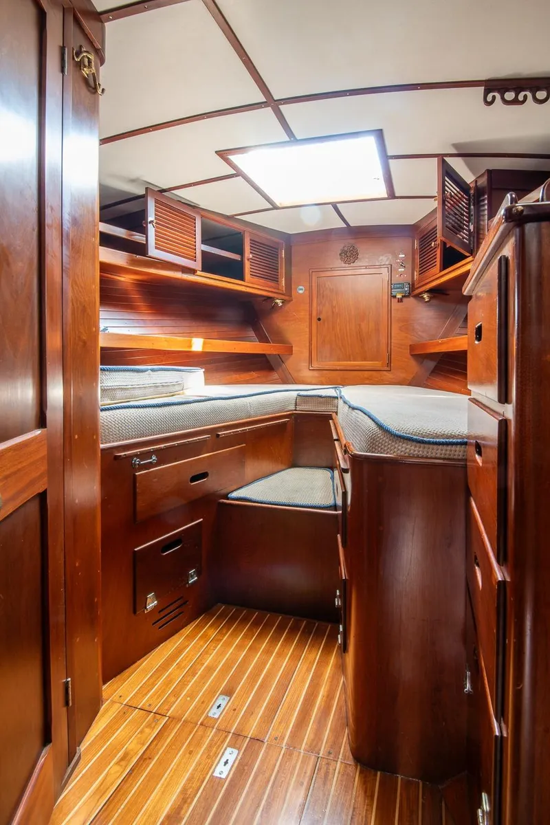 Slide: The Image of 1976 Hinckley SW50 yacht interior with wooden cabinetry and cozy sleeping area. - 29