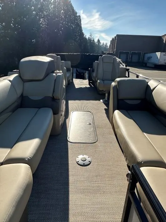 Slide: The Image of 2024 Regency 230 DL3 pontoon boat interior with beige seating and carpeted floor. - 5