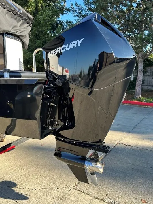 Slide: The Image of 2024 Regency 230 DL3 boat with a Mercury outboard motor, parked outdoors. - 6