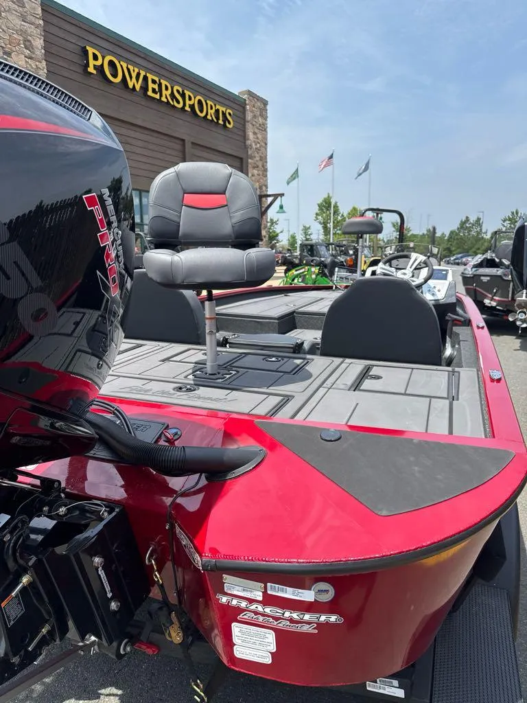 Slide: The Image of 2025 Tracker Savage 215 boat at Powersports dealership, featuring red and black design. - 3