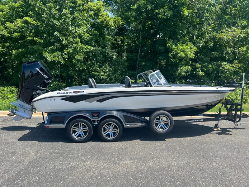 Slide: The Image of 2025 Ranger 621FS Cup Equipped boat on trailer, parked outdoors with lush green background. - 2