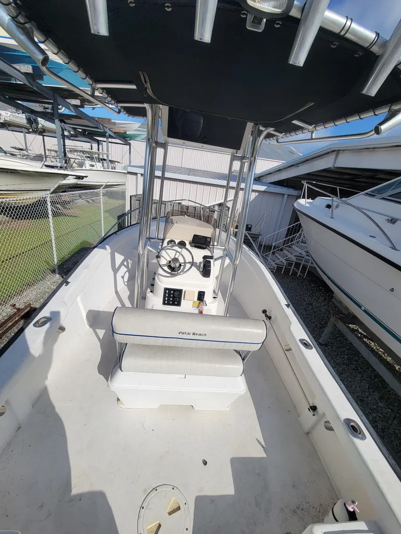 Slide: The Image of 2005 Palm Beach 181 boat interior with console and seating, docked near other boats. - 2