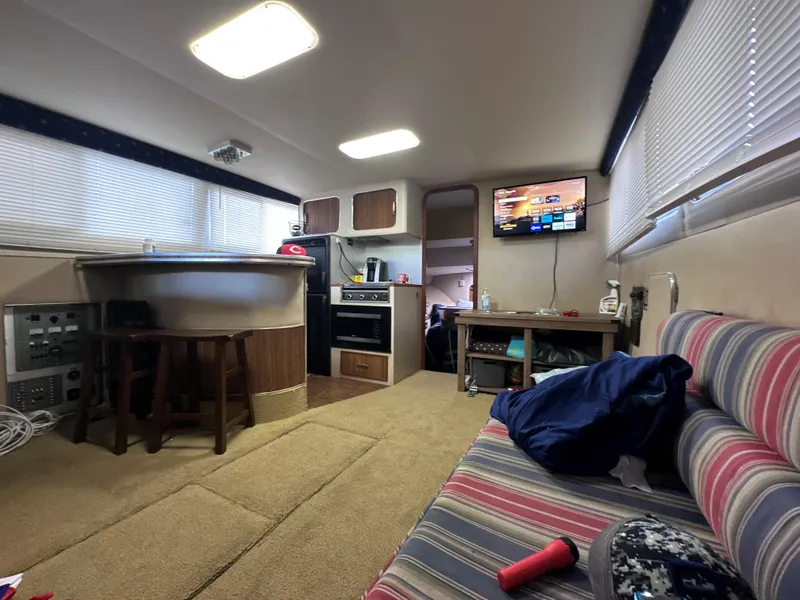 Slide: The Image of 1985 Chris-Craft 381 Catalina interior with kitchen, seating, and TV. Cozy and well-lit cabin. - 6