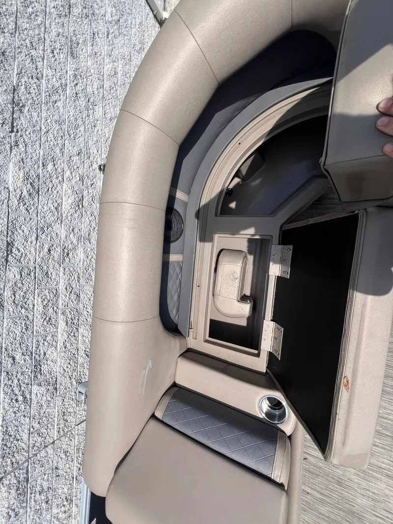 Slide: The Image of 2022 Bennington 22 LS boat interior with open storage compartment and cup holder. - 14