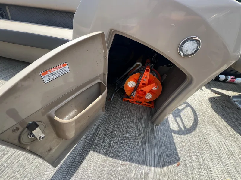 Slide: The Image of Open storage compartment on 2022 Bennington 22 LS boat, revealing safety equipment inside. - 15