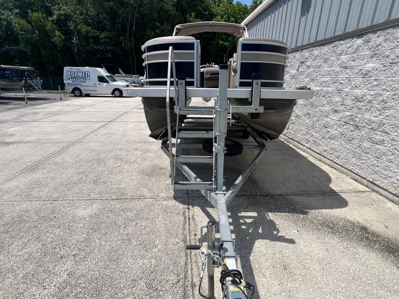 Slide: The Image of 2022 Bennington 22 LS pontoon boat on trailer, parked outdoors near a building. - 4