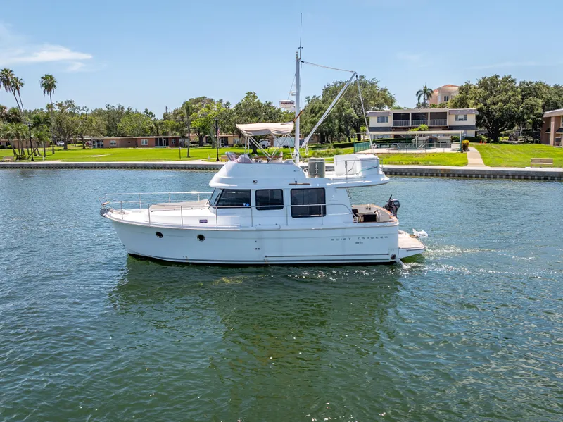 Slide: The Image of 2015 Beneteau Swift Trawler 34 cruising on a sunny day near waterfront homes. - 1