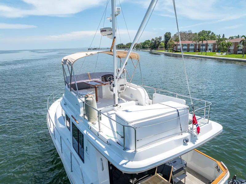Slide: The Image of 2015 Beneteau Swift Trawler 34 on serene water, showcasing upper deck and scenic shoreline. - 10