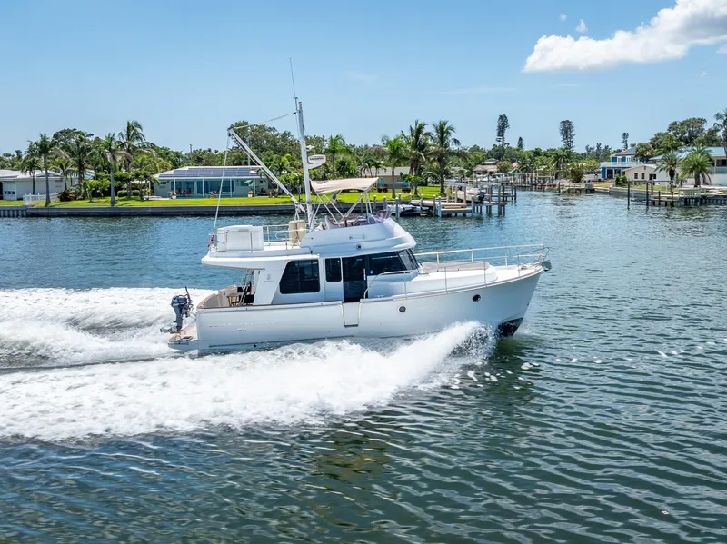 Slide: The Image of 2015 Beneteau Swift Trawler 34 cruising on a sunny day near waterfront homes. - 13
