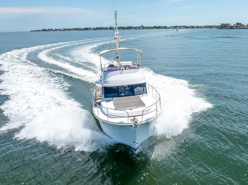 Slide: The Image of 2015 Beneteau Swift Trawler 34 cruising on open water, creating a dynamic wake. - 19