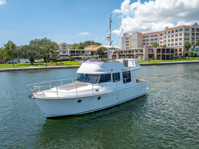 Slide: The Image of 2015 Beneteau Swift Trawler 34 cruising on a sunny day near waterfront buildings. - 2
