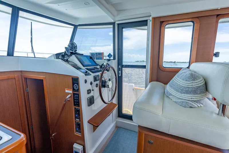 Slide: The Image of 2015 Beneteau Swift Trawler 34 helm with steering wheel, navigation equipment, and comfortable seating. - 34