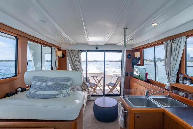 Slide: The Image of Interior of 2015 Beneteau Swift Trawler 34, featuring cozy seating, kitchen, and ocean view. - 40