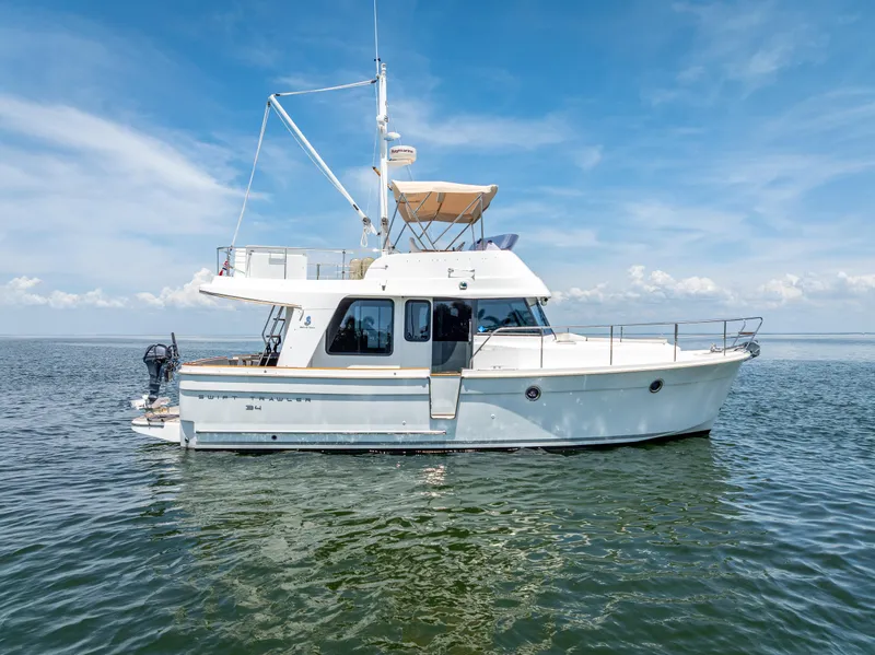 Slide: The Image of 2015 Beneteau Swift Trawler 34 on calm water under a clear blue sky. - 6
