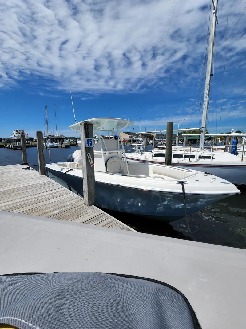 Slide: The Image of 2022 Sailfish 220 CC boat docked at marina under clear blue sky. - 3