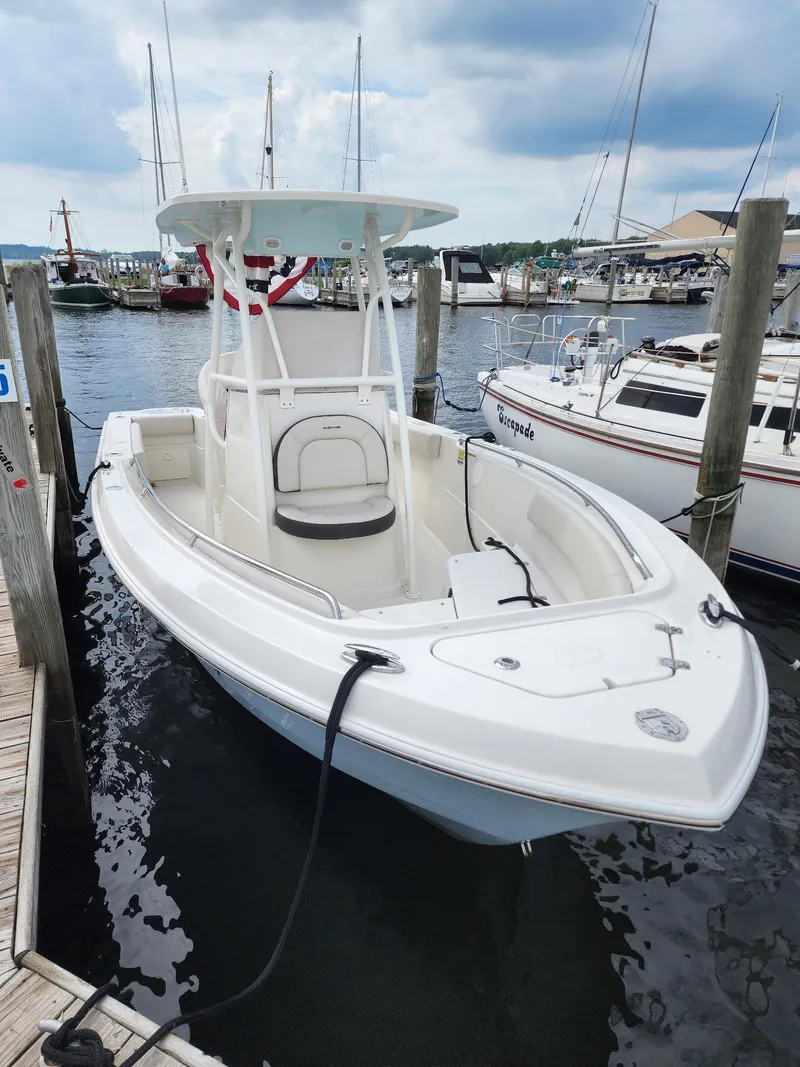 Slide: The Image of 2022 Sailfish 220 CC boat docked at a marina, surrounded by other vessels. - 4