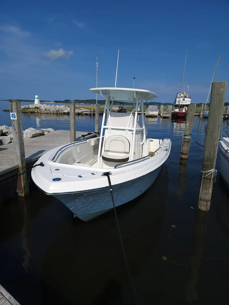 Slide: The Image of 2022 Sailfish 220 CC boat docked at a marina under clear blue skies. - 7