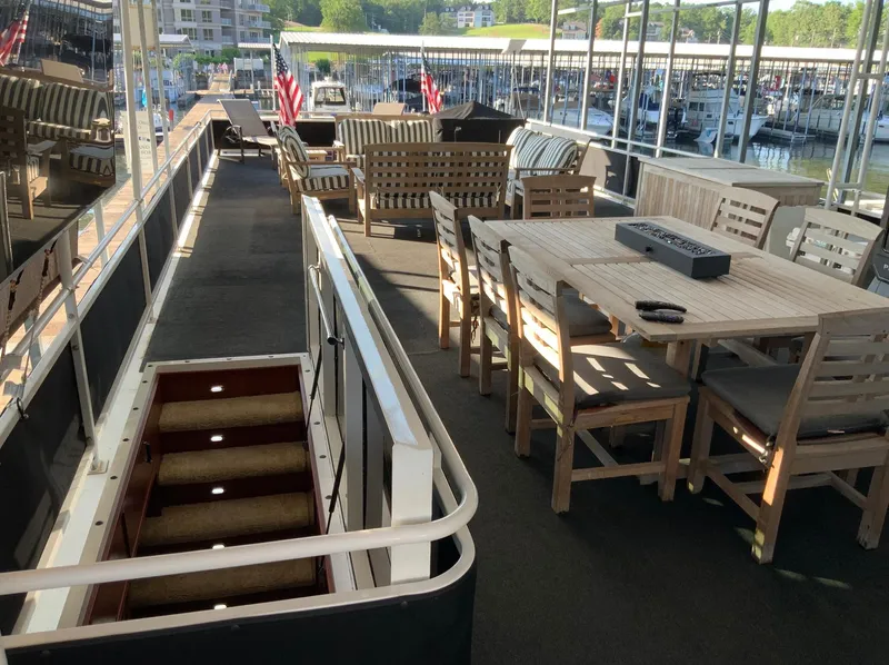 Slide: The Image of Outdoor seating area on a 2007 Skipperliner 640 houseboat, featuring wooden furniture and marina view. - 3