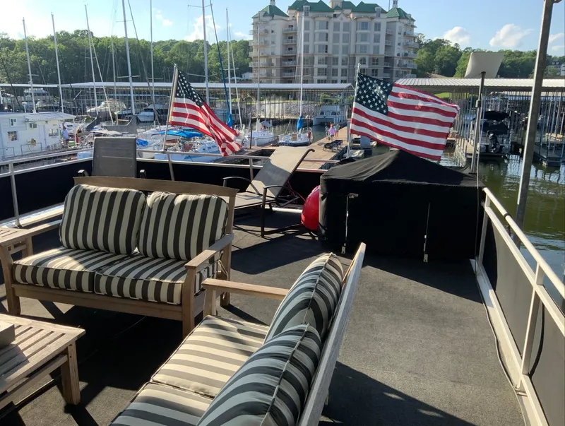Slide: The Image of 2007 Skipperliner 640 houseboat deck with striped seating and American flags at marina. - 8