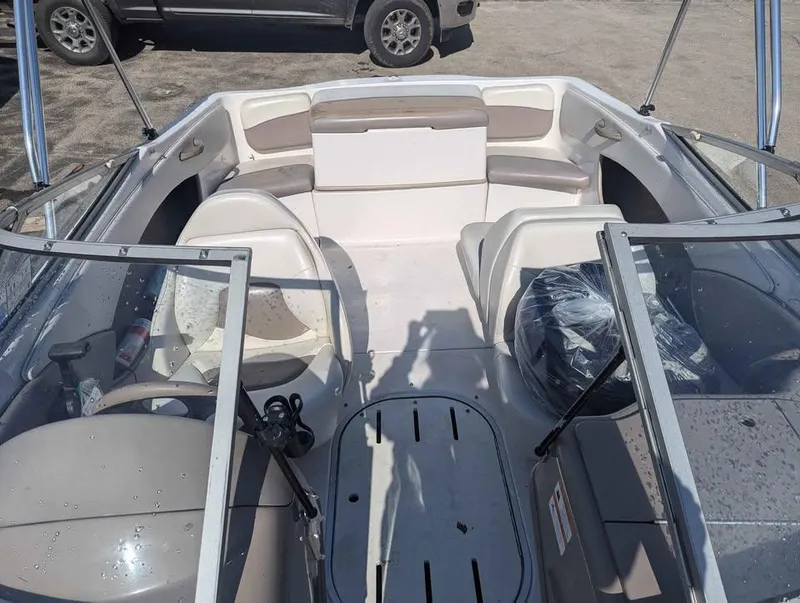 Slide: The Image of 2003 Four Winns Freedom 170 boat interior with seating and windshield, parked on pavement. - 11