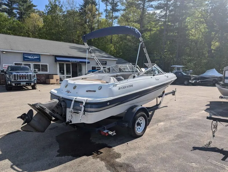 Slide: The Image of 2003 Four Winns Freedom 170 boat on trailer in parking lot, surrounded by trees. - 4
