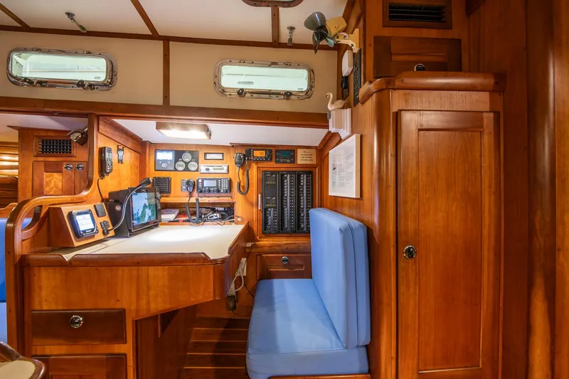 Slide: The Image of Navigation station inside a 1997 Valiant 42 yacht, featuring wooden cabinetry and blue seating. - 16